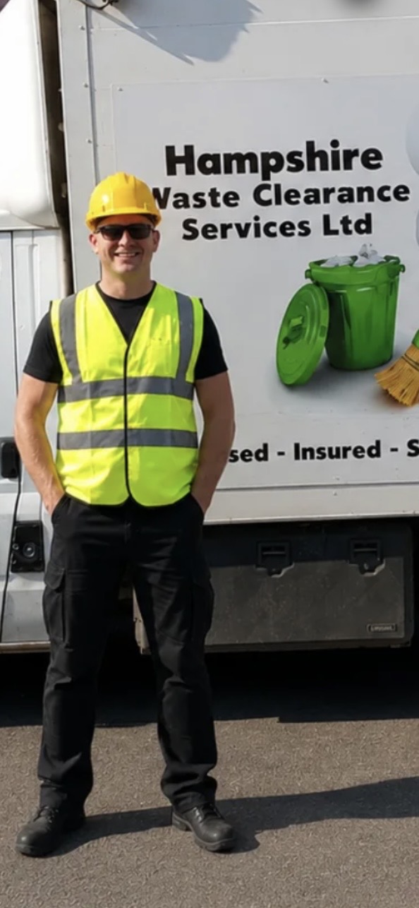 Jason, owner of Hampshire Waste Clearance Services Ltd, standing in hi-vis and hard hat beside the company's branded waste clearance truck.